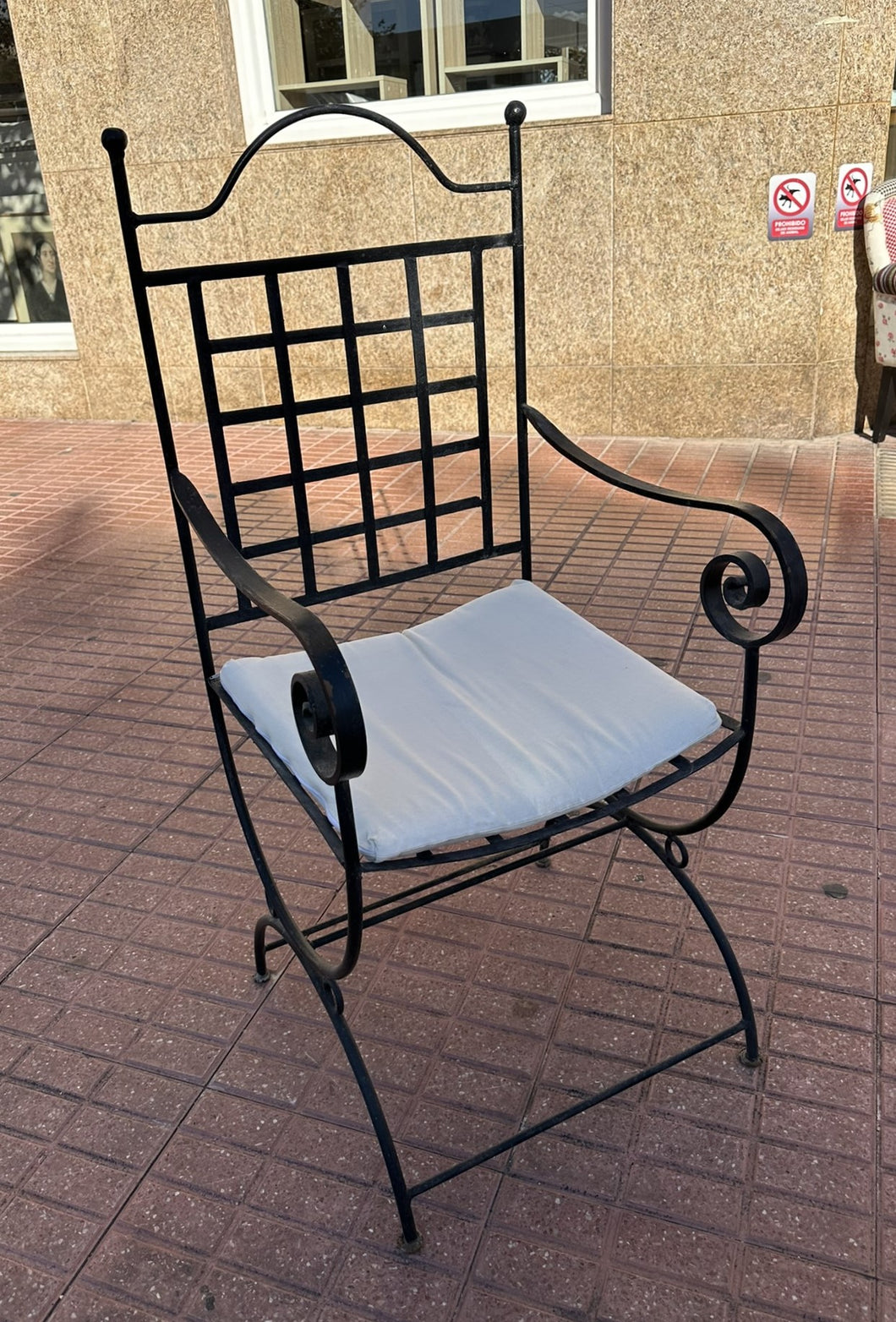 1100 - Heavy wrought iron armchair with cushion.